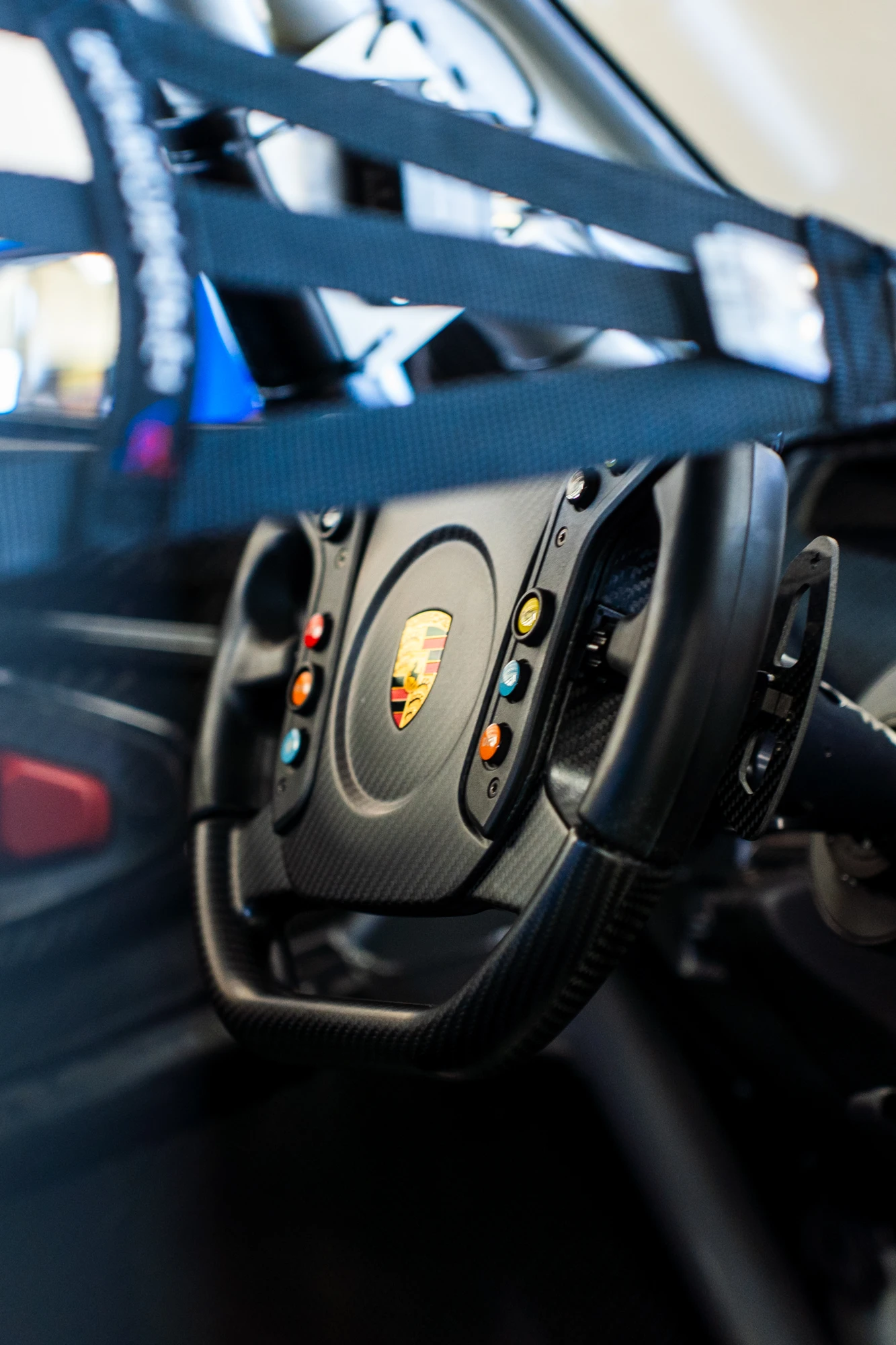 Carbon-fiber Porsche racing steering wheel viewed through the window net
