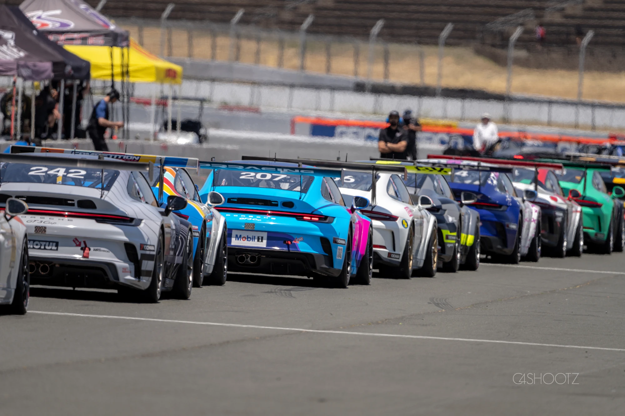 Porsche race cars lined up in the paddock