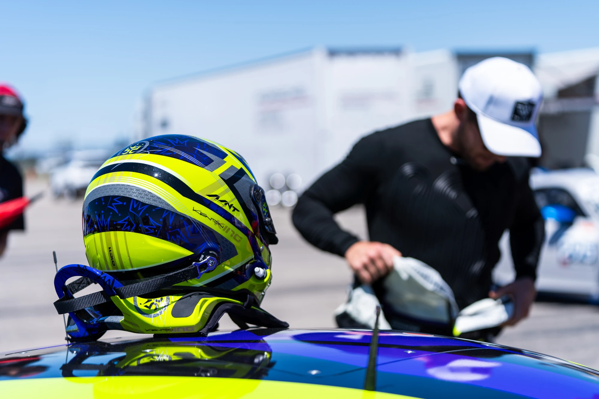 Purple and lime helmet resting on the race car during preparations