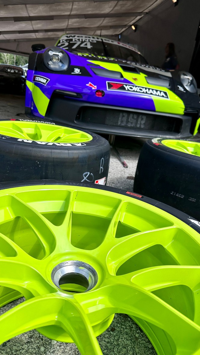 Lime racing wheels ready beside the purple Avant-liveried Porsche